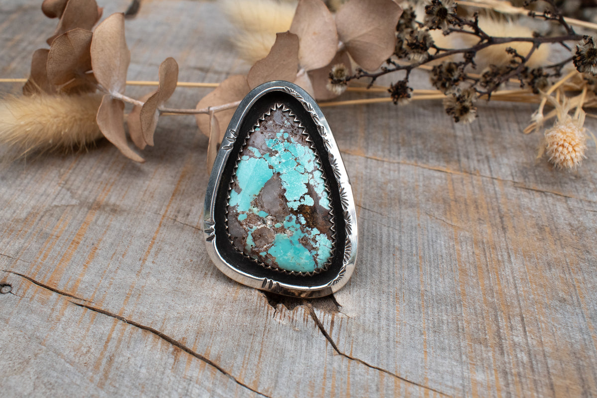 Large Kingman turquoise set in shadowbox setting on split shank ring band. Hand stamped designs.